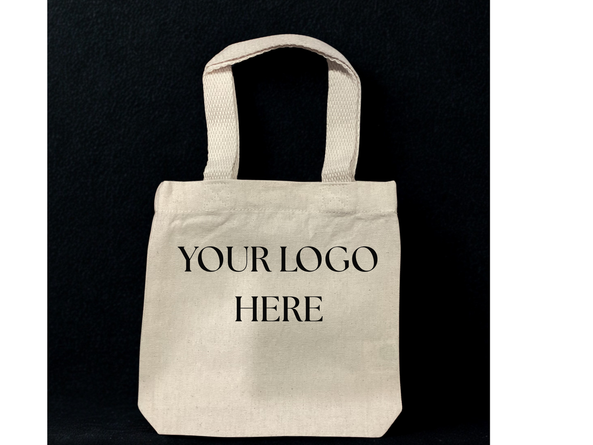 A natural canvas tote bag with black printed text reading 'YOUR LOGO HERE' on the front, set against a solid black background.

8"W x 8"H x 1.5"D
14" Handles